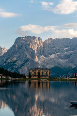 Fototapeta premium Buildings along the shoreline are reflected in the calm waters of Lake Misurina in the Italian Dolomites, just before sunset.