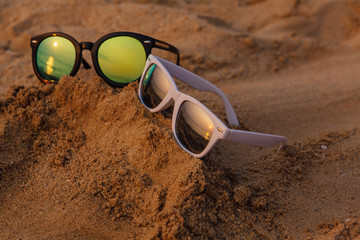 Fototapeta na wymiar Sunglasses lying on the sandy beach on the sunset.