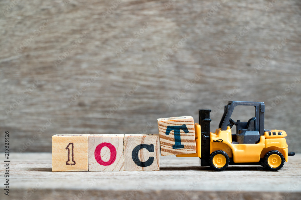 Wall mural Toy forklift hold block T to complete word 1oct on wood background (Concept for calendar date in month October)