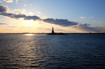 Hudson river view with the silhouette of the statue of Liberty against the blue sky and infinite horizon at sunset. New York City iconic tourist attraction.