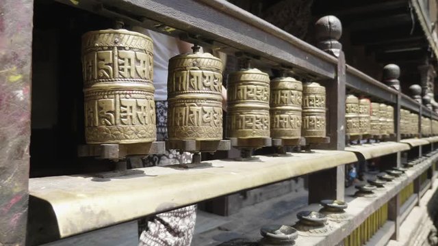 Woman spins prayer wheels in Patan, Durbar Square, Kathmandu valley, Nepal.