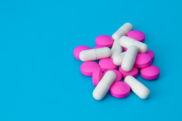 Obraz na płótnie Canvas A pile of large pills of pink and white color close-up on a blue background.