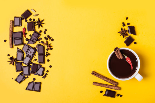 Hot chocolate cup with hot pepper and cinnamon. Ingredients for its cooking on yellow background.