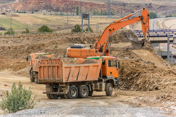 Trucks and excavators moving earth for the construction of a highway