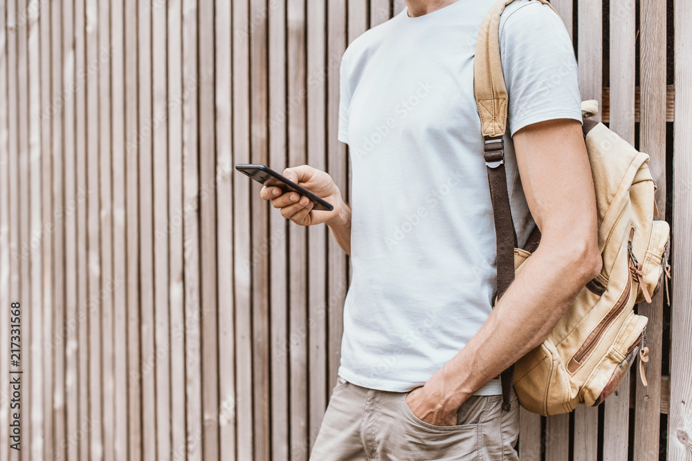 Wall mural Young man using smartphone in the city. Student men texting on his mobile phone outdoor