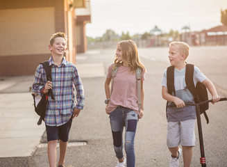 Candid Photo of a group of smiling elementary school students in the playground after school.  Back...