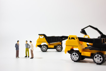 three miniature businessman with construction car.