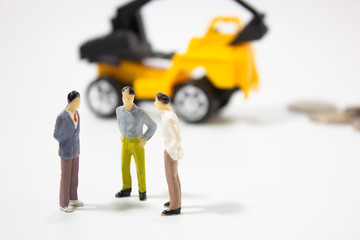three miniature businessman with excavator car background.