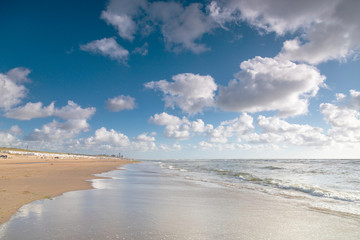 Bank of the blue sea with wet sand and clouds