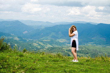 Naklejka na ściany i meble A young girl loves to travel and conquer the peaks of the mountains