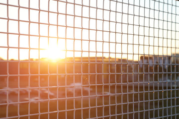 The sunlight shines through a lattice fence