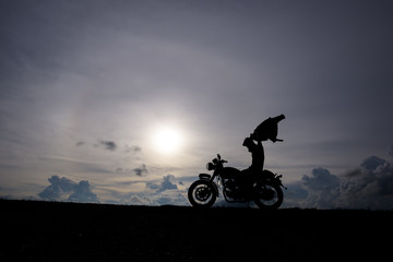 Motorcycle or motorbike Silhouette with male rider standing at the river.