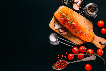 Delicious Salmon fillet with various spices on black background