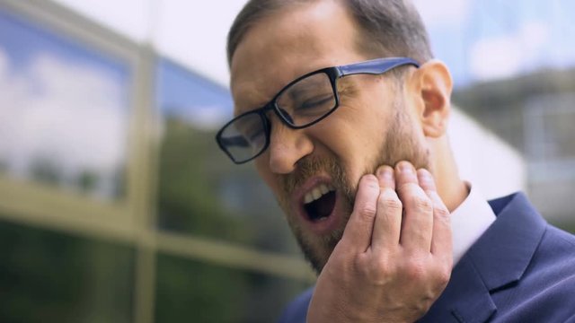 Man in suit feeling tooth ache, dental care, inflammation of pulp, medicine