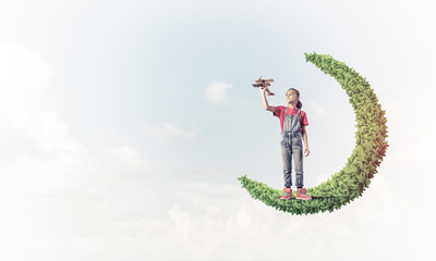 Concept of careless happy childhood with girl on green moon