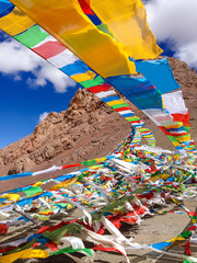 wind wavering Buddhist Tibetan Chinese prayer flags with Sanskrit calligraphy written decorating mountain valley in Tibet, China, Asia. Belief, Faith, Buddhism Religion, Ceremonial Banner Decoration.