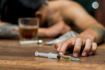 Young man with beard, lost in the vices of alcoholism, smoking and drug addiction