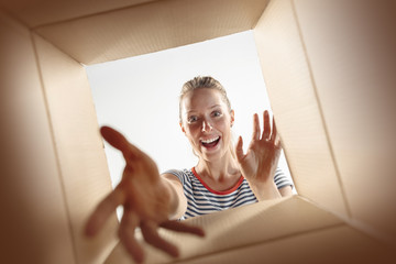 The surprised woman unpacking, opening carton box and looking inside. The package, delivery,...