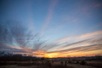 Obraz premium Partially Cloudy Dramatic Sunset Sky over Winter Fields and Meadows.