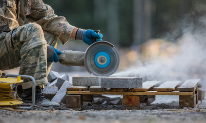 worker cuts stone tiles with electric saws