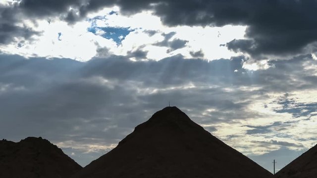 Beautiful heap clouds on the blue sky moving over sandy hills in the form of Egyptian pyramids.
