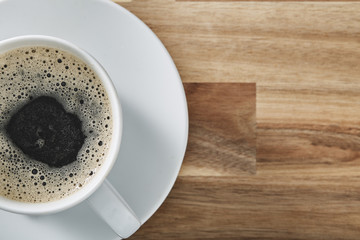 Obraz premium Cup of coffee on wooden table with copy space. Top view.
