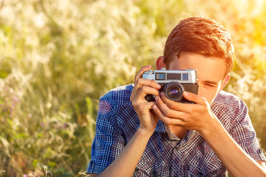 a young man with a camera taking pictures of the natural background sun rays tinted