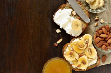 Toast with cream cheese, topped with banana, almonds and honey, top view, copy space