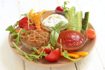 Plate with three healthy different dips and vegetables