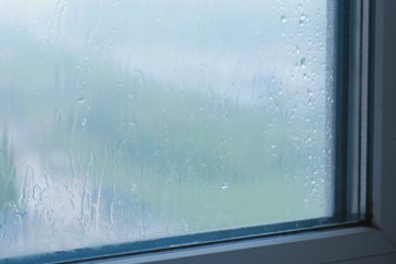 Raindrops flow down the window close-up indoor