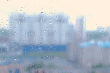 Raindrops flow down the window close-up. View of sity and road from wet window, blur