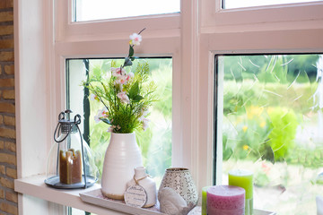 home decoration on windowsill with colorful flowers and white vase on a sunny day