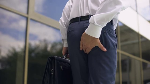Office worker feeling hemorrhoid pain while walking, sedentary lifestyle, health