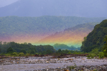 Mountain landscape with a rainbow over river.