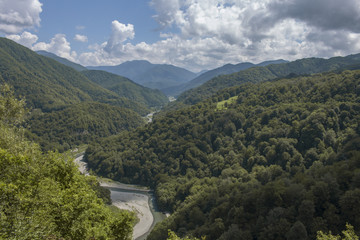 Fototapeta na wymiar top view wild river flowing between green mountains on a clear summer day