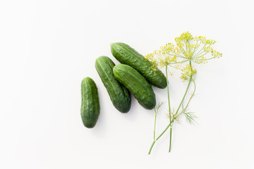 Young cucumbers with greens on a white background
