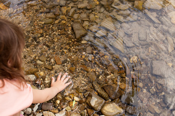 Girl 4 years touches the water of a mountain river