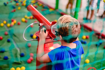 Child playing at a summer fair with a cannon of colored balls of compressed air.