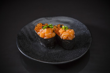 Ikura Salmon Nigiri, Salmon Sushi topped with salmon egg, salmon ikura nigiri served on traditional Japanese food on ceramic dish, Japanese food style,  on black background, selective focus