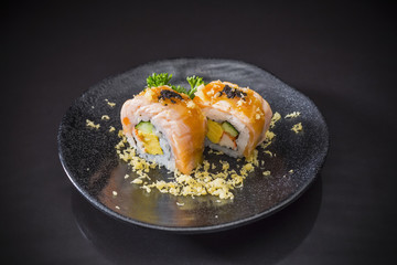 Salmon Roll with spicy sauce served on traditional Japanese food on ceramic dish, Japanese food style, Sushi Menu, salmon sushi roll on black background, selective focus