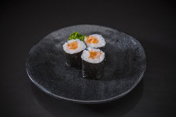 Salmon Maki served on traditional Japanese food on ceramic dish, Japanese food style, Sushi Menu, Salmon sushi maki roll on black background, selective focus
