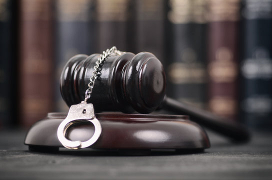  Judge Gavel and Handcuffs on a black wooden background.