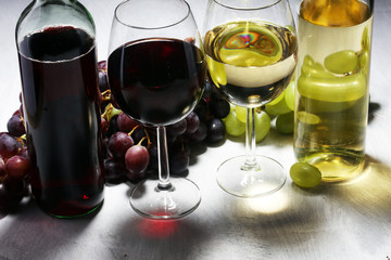 White wine and red wine in a glass with fall grapes, white stone background.