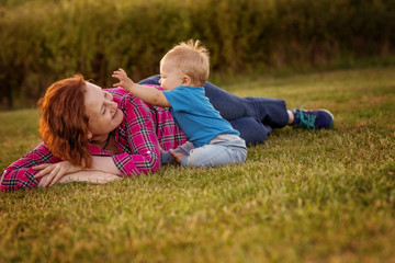 Baby first year playing with mother on the grass.