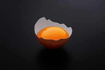 Yolk in the eggshell on black background