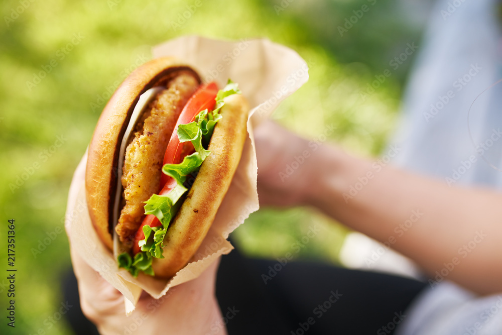 Wall mural woman holding crispy chicken sandwich from first person view