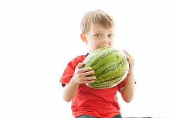 Fototapeta premium A cute boy and a big green watermelon. The child smiles and rejoices.
