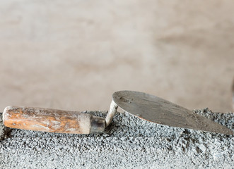 Dirty trowel on the incompleted brick wall.