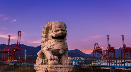 Stone lion statue near the port of Vancouver at sunset.