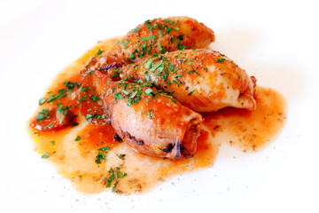 Squid stuffed cooked in a pan with oil and tomato sauce. photographed in the studio on a white plate. Ready to eat.
